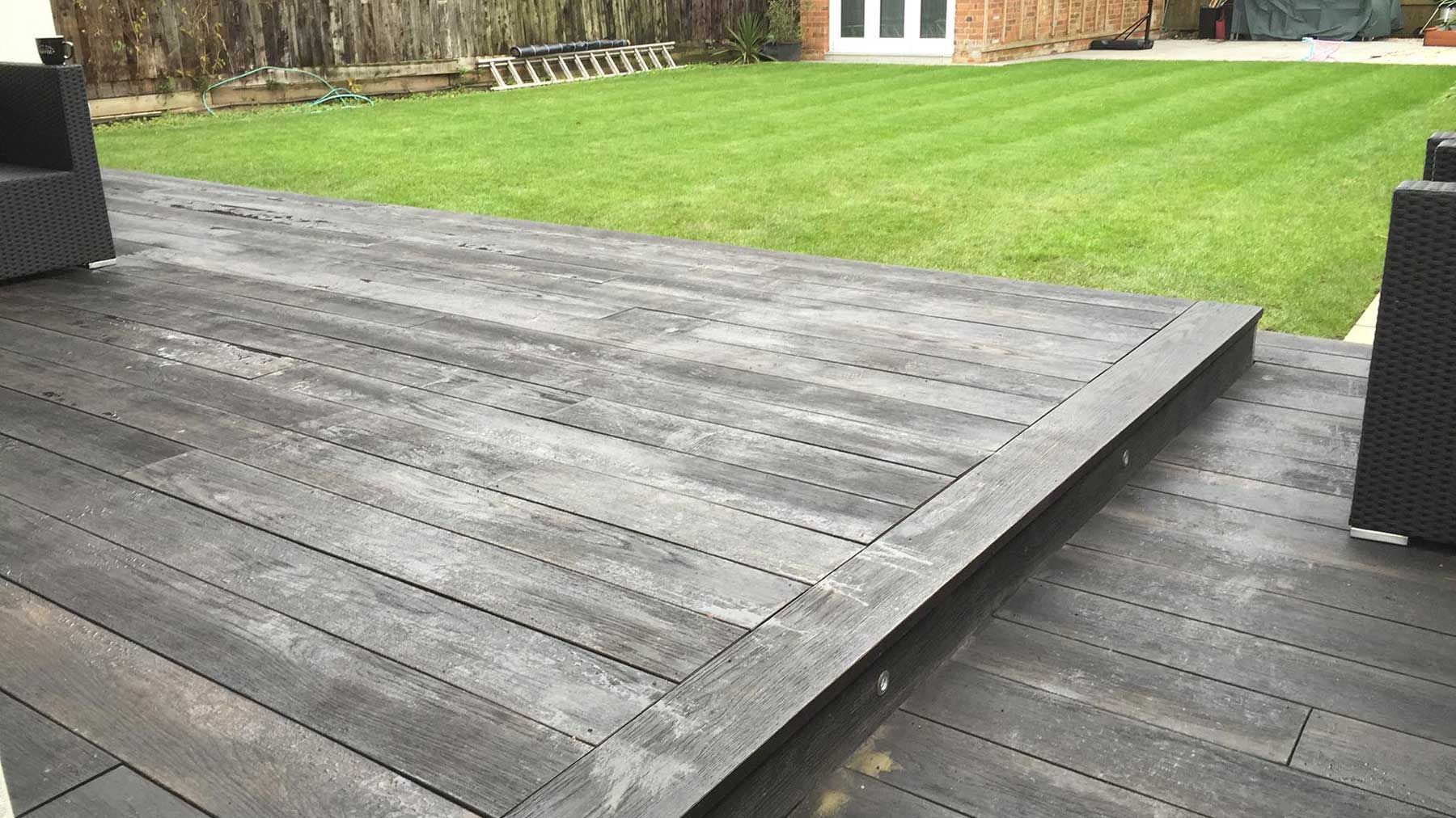 Dark gray wooden deck with a grassy lawn in the background.