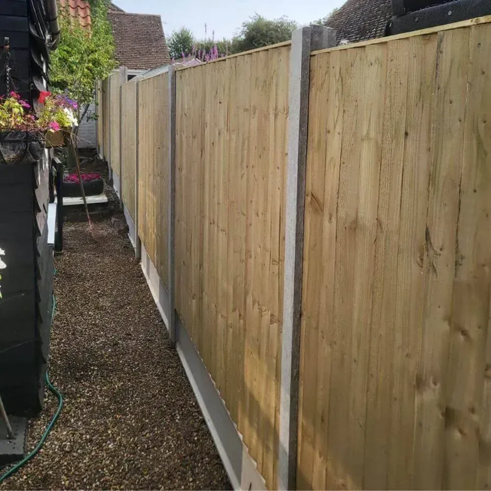 Wooden fence with concrete posts and gravel path.