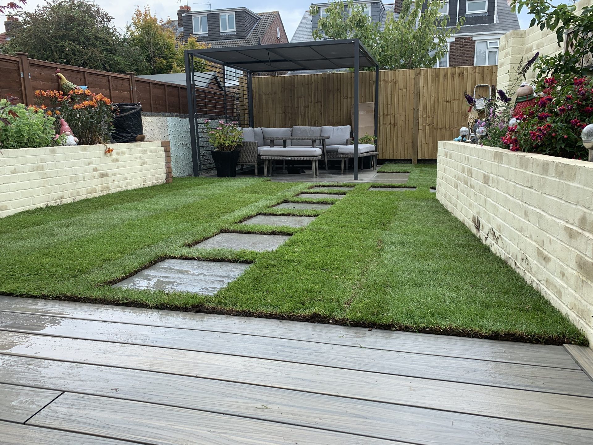 A backyard with a patio, lawn, seating area under a pergola, and brick walls.