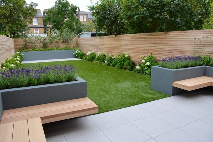 Modern backyard with lawn, gray planters with lavender, wooden benches, and wooden fence.