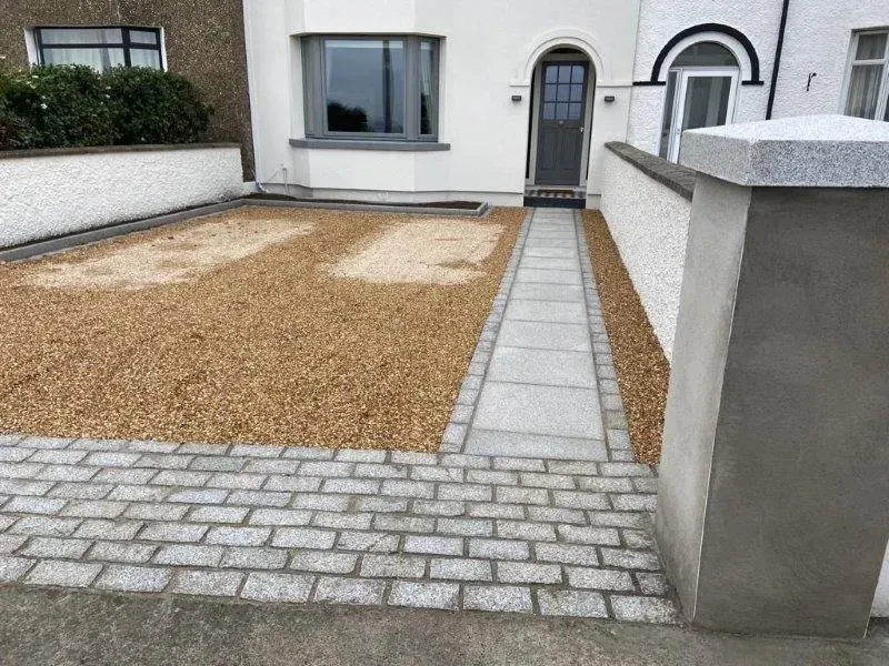Driveway with gravel and stone pathway leading to a front door. Gray walls and a mailbox.