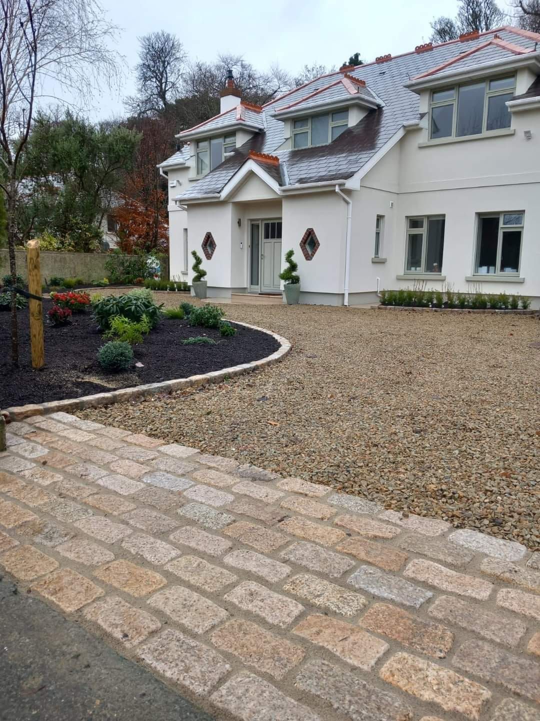 White house with a gravel driveway and stone walkway; landscaped front yard.