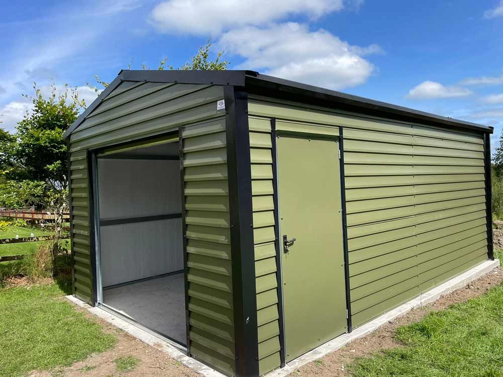 Green metal shed with open garage door and side door, black trim.