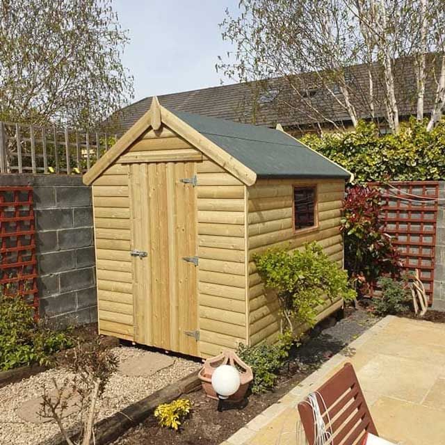 Wooden garden shed with a green roof, door, and small window, surrounded by plants and brick walls.