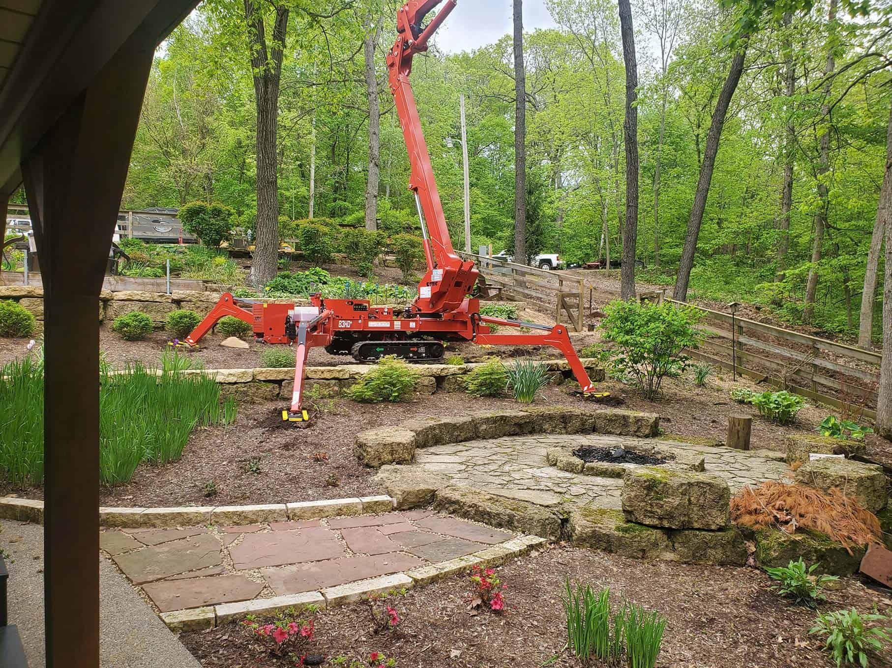 A red crane is sitting in the middle of a garden.