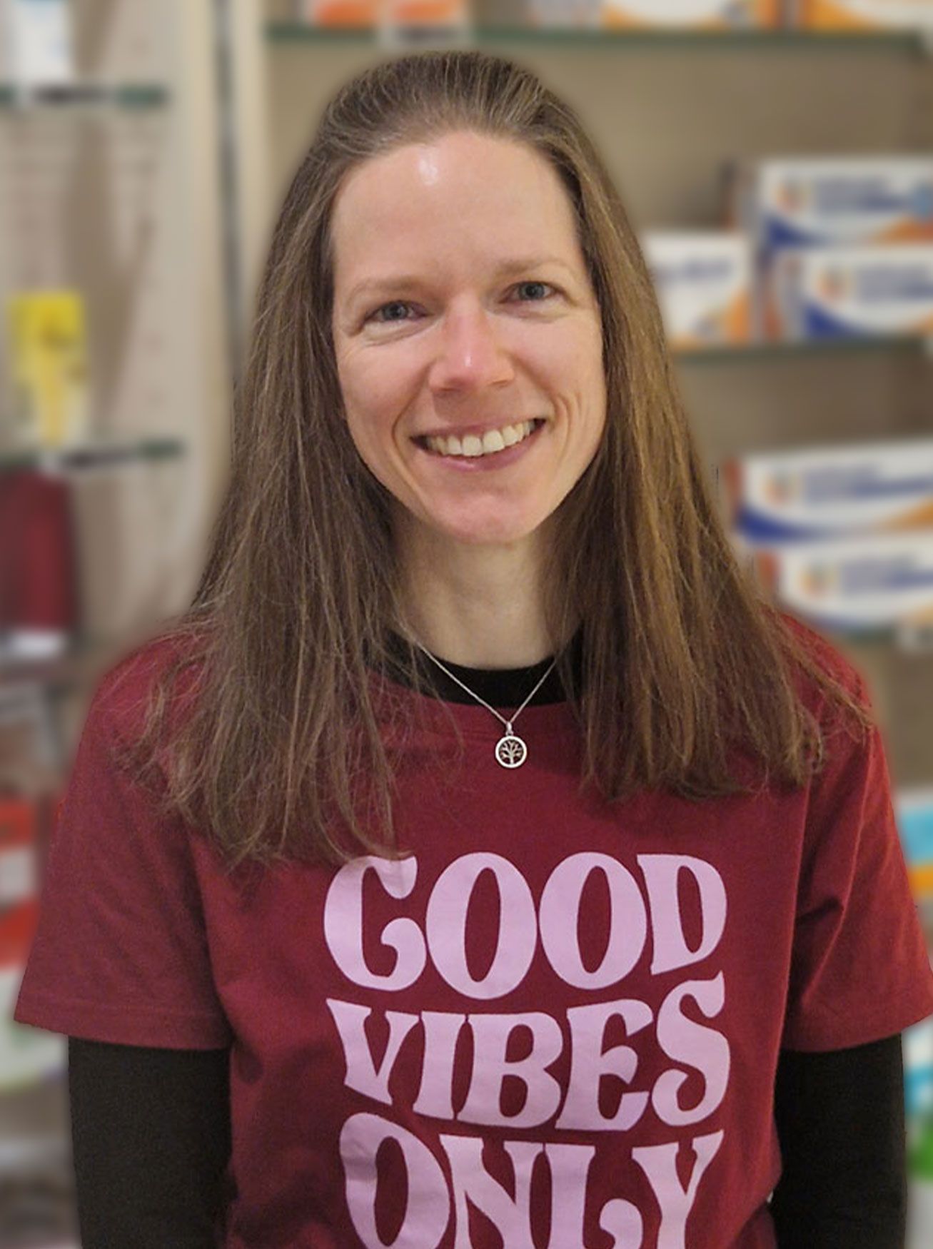 Eine Frau, die ein rotes T-Shirt mit der Aufschrift „Good Vibes Only“ trägt, lächelt.