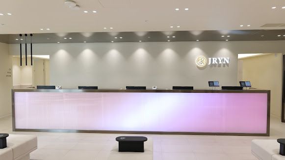 Modern minimalist lobby with a white reception desk, red seating, and soft pink lighting.
