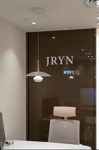 Modern lounge with gray sofas, glass walls, and orange accent chairs in a sleek office interior