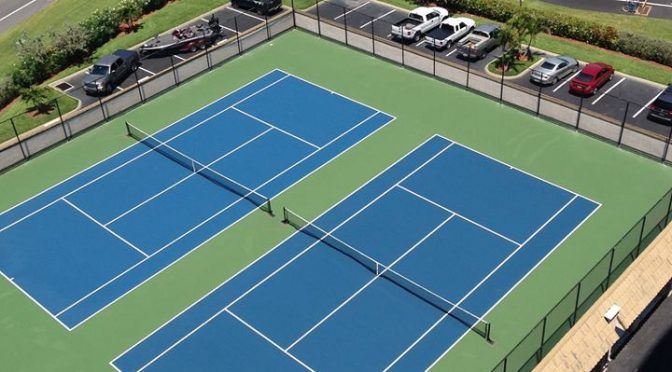 An aerial view of a tennis court with cars parked in front of it.