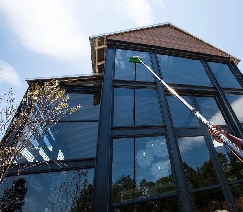 A man is cleaning a brick building with a high pressure washer.