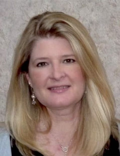 Portrait of a smiling woman with long blonde hair wearing earrings against a neutral background