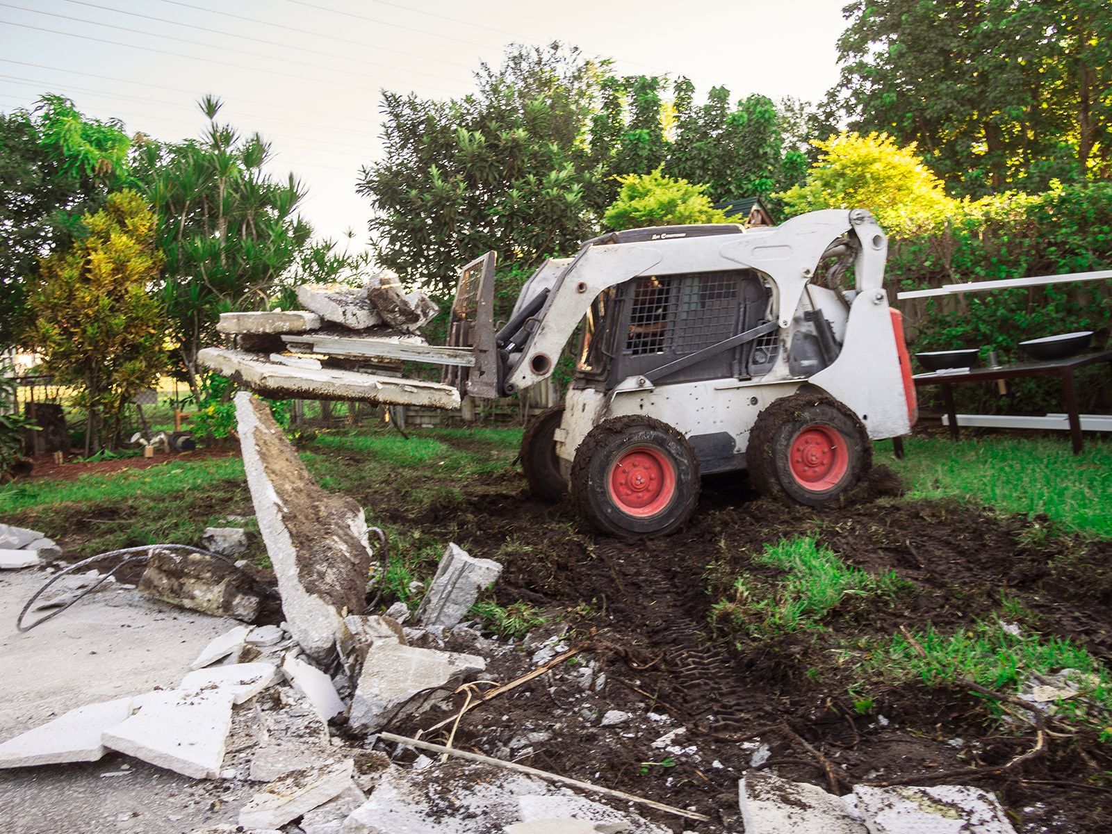 Two construction workers using jackhammers on concrete, creating dust clouds.