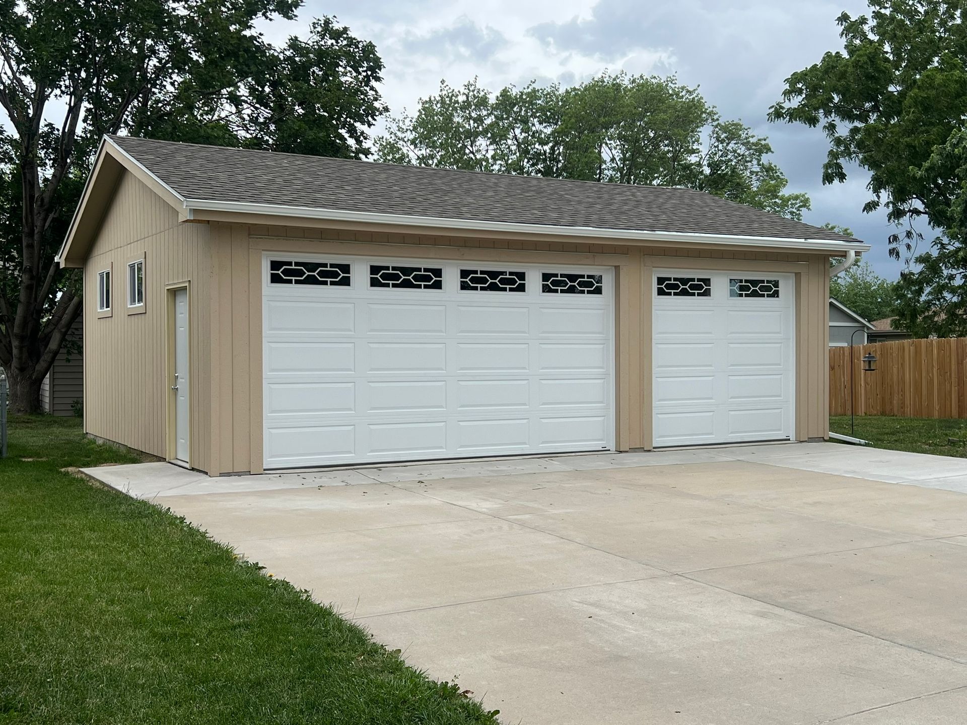 Two dark gray garage doors, one with three square windows, on a white building.