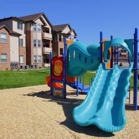 a playground with a blue slide in front of a building