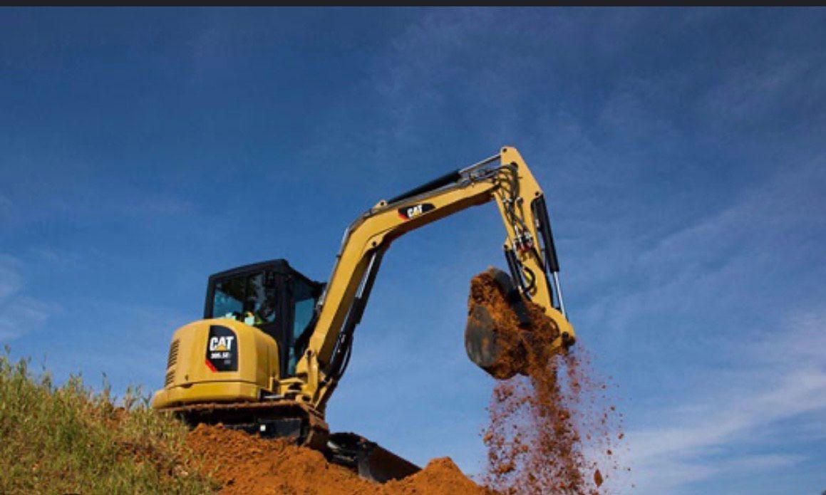 A yellow excavator is digging a hole in the ground.
