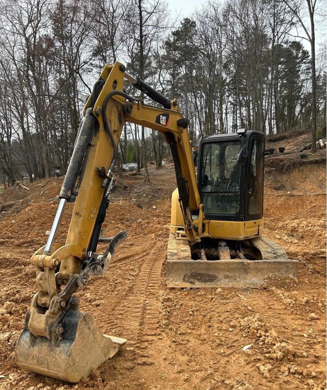 A yellow excavator is sitting on top of a dirt field.
