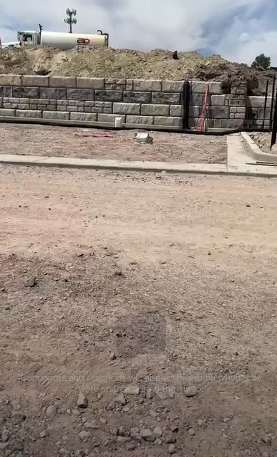 A brick wall is being built on top of a dirt field.
