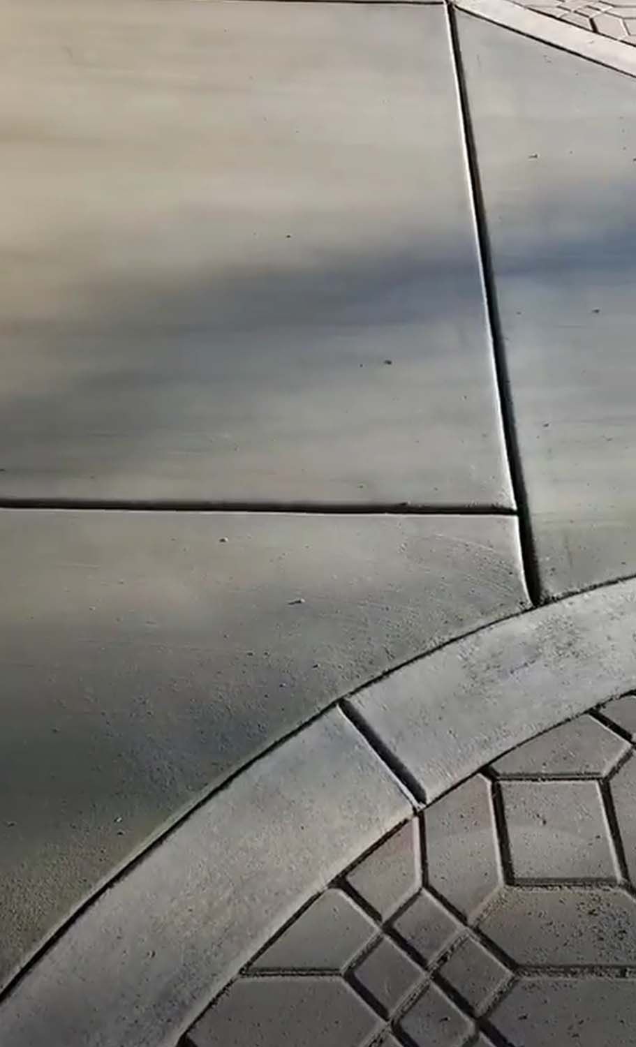 A close up of a concrete sidewalk with a brick border.