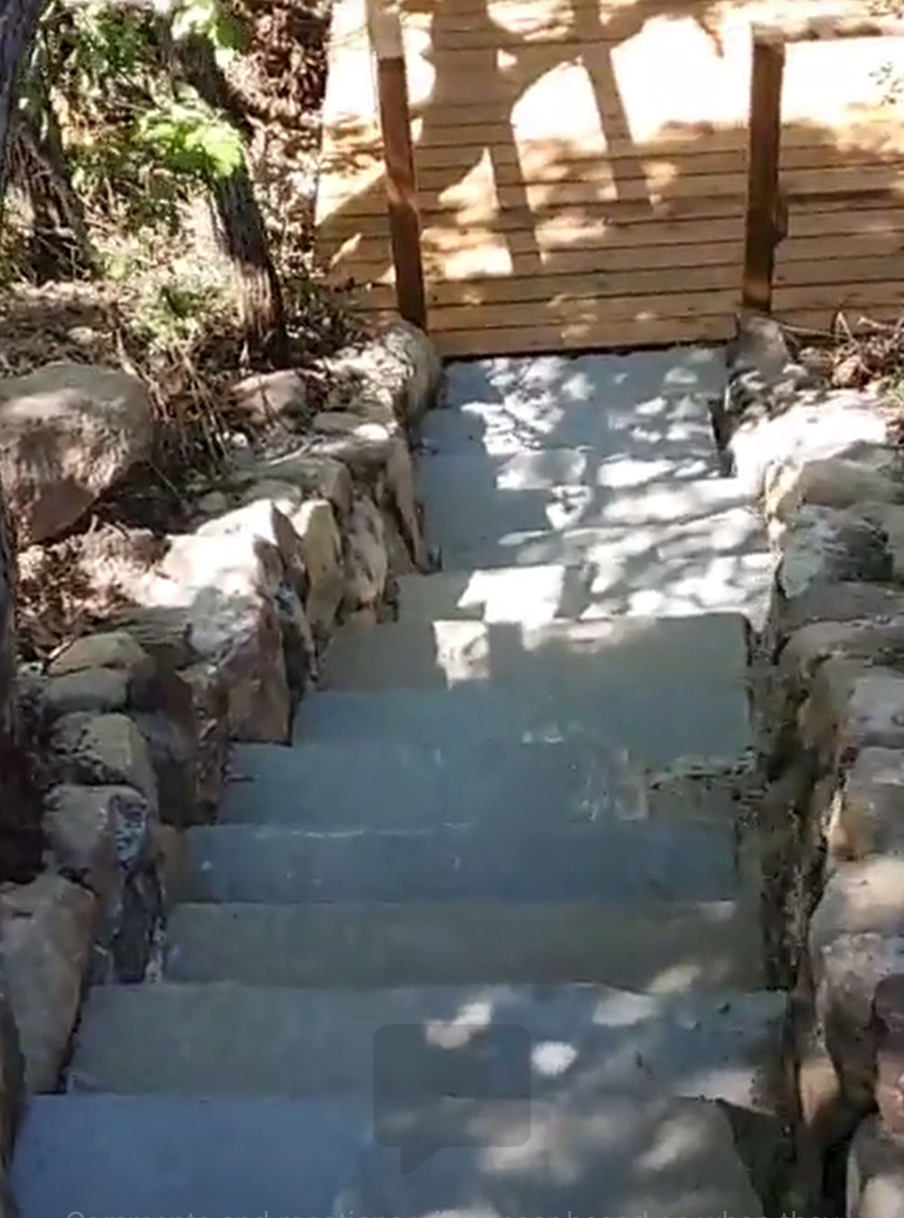 A set of stairs leading up to a wooden bridge surrounded by rocks.