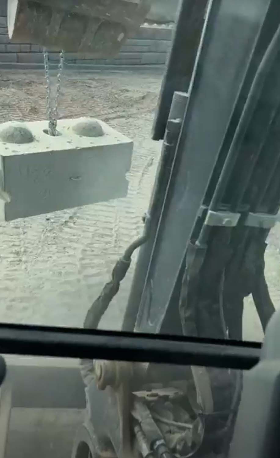 A person is sitting in a car looking out the window at a construction site.