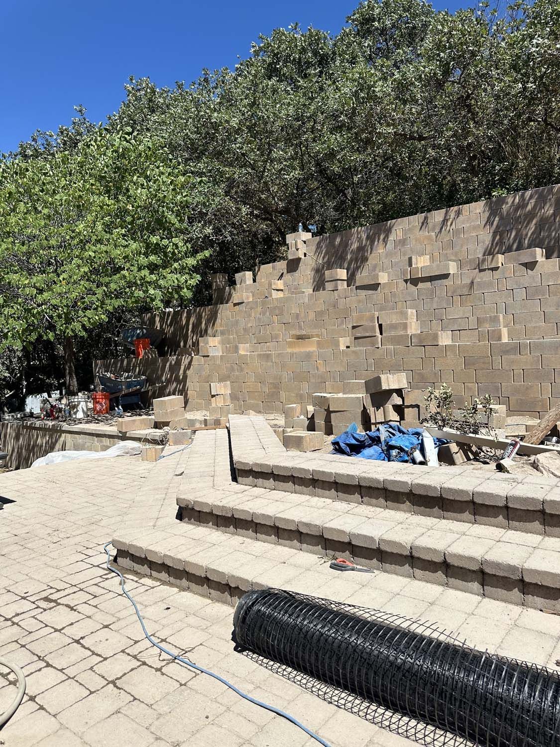 A large brick wall is being built next to a brick walkway.