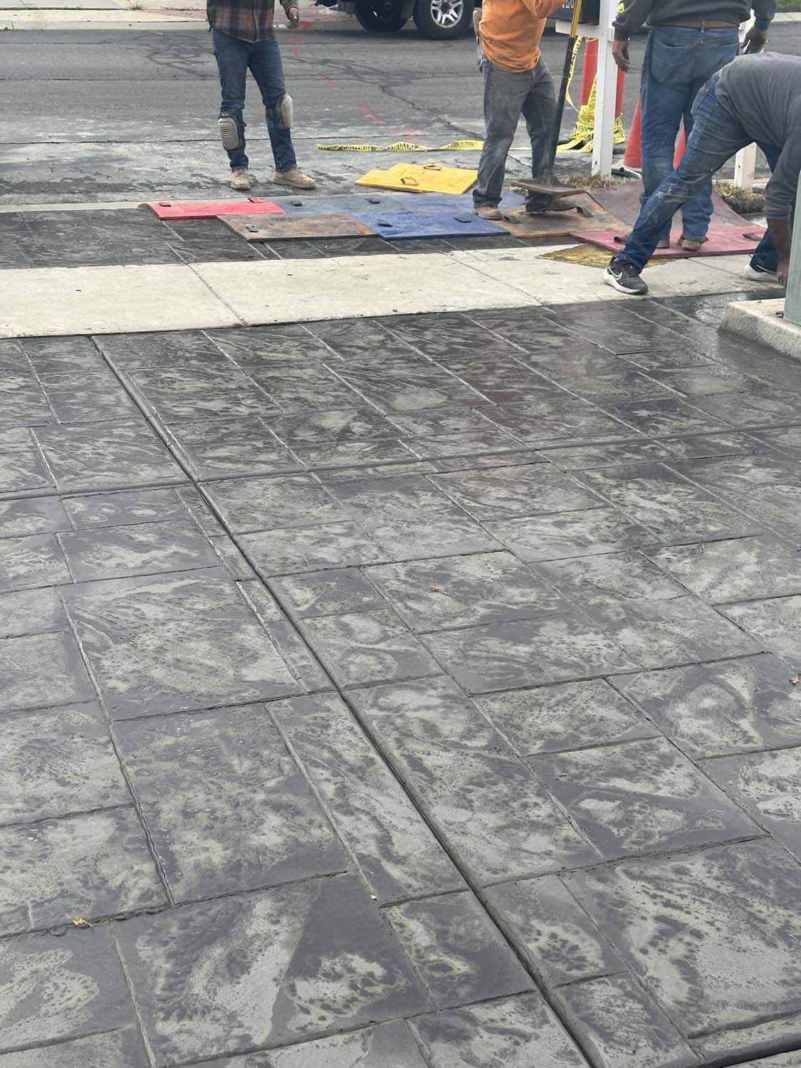 A group of men are working on a concrete driveway.