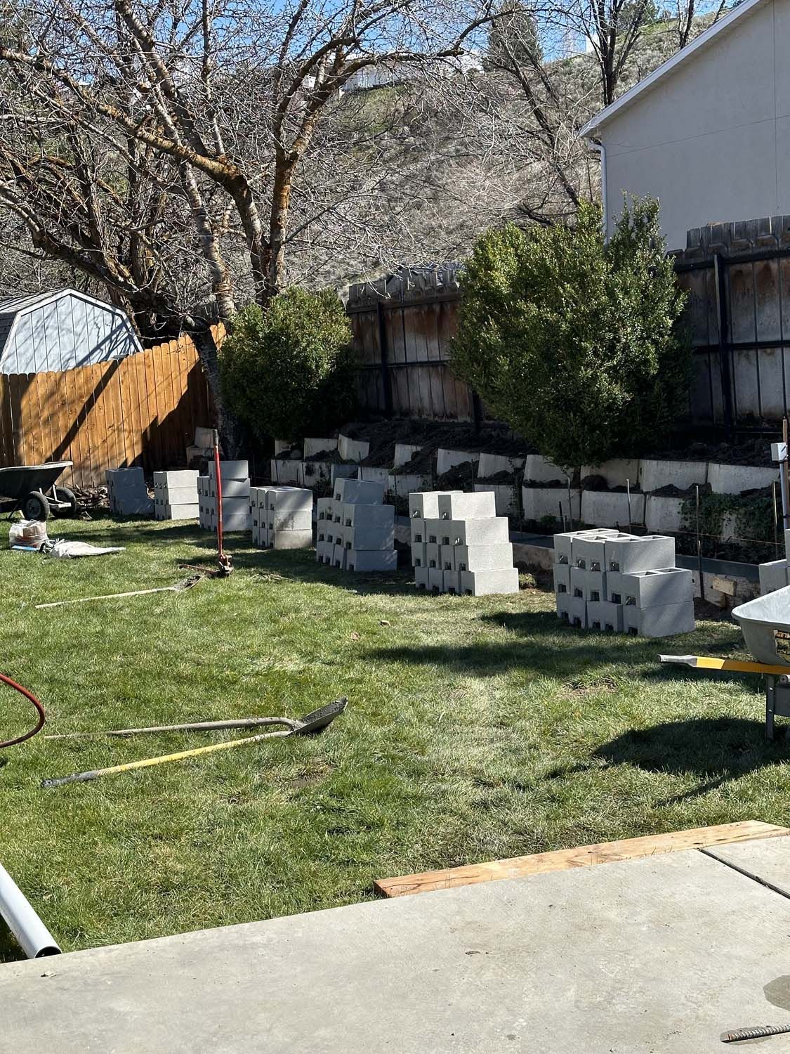 A lawn with a lot of bricks in it and a house in the background.