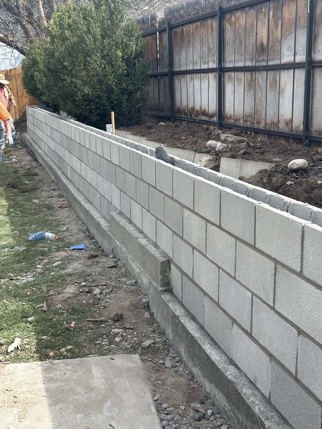 A Brick Wall is Being Built in a Backyard Next to a Fence