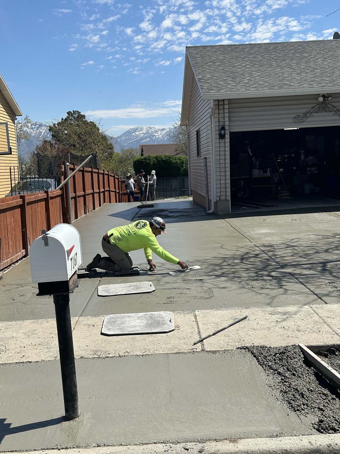 A Man is Working on a Concrete Driveway in Front of a House