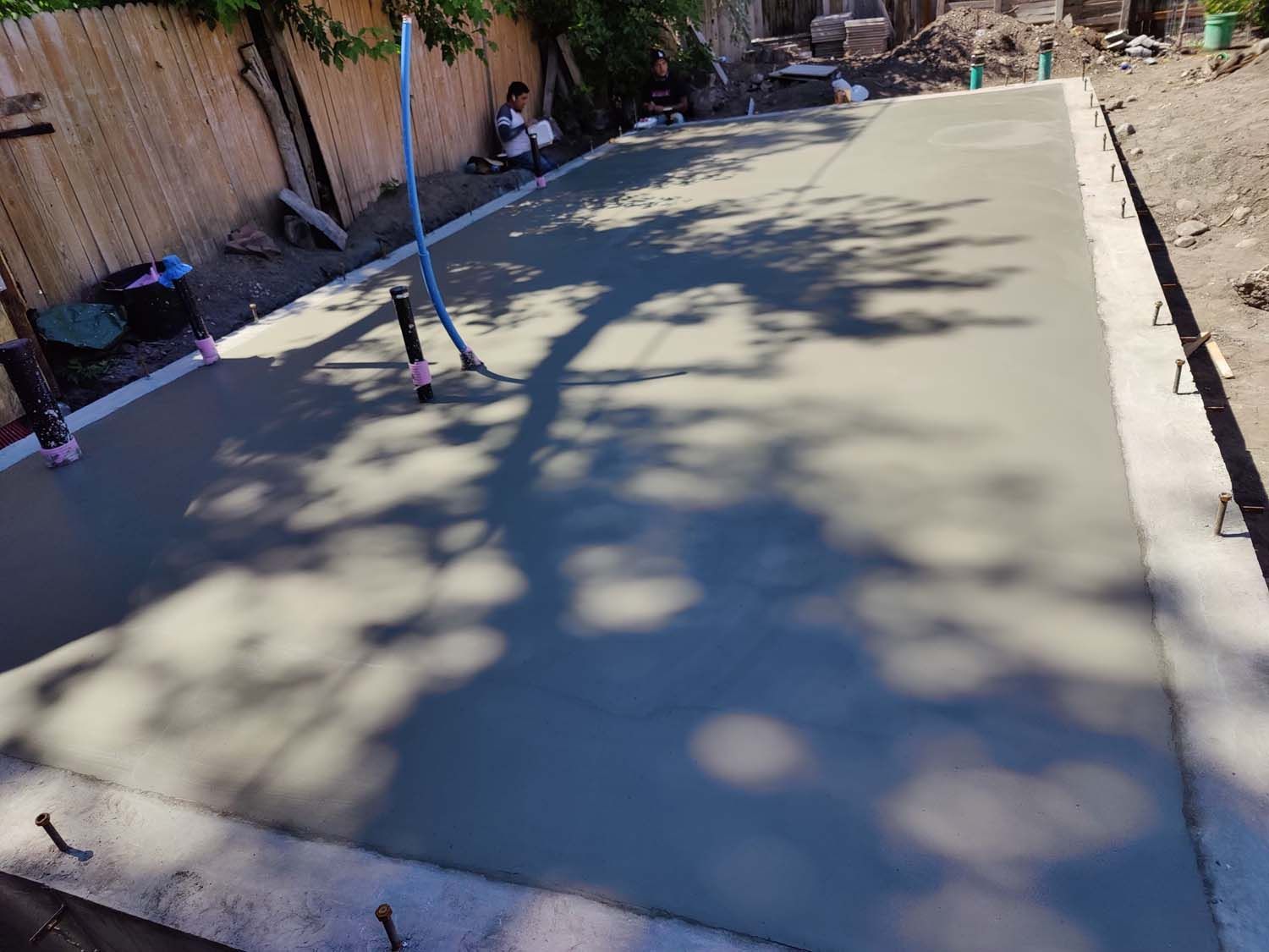 A concrete driveway is being built in a backyard.