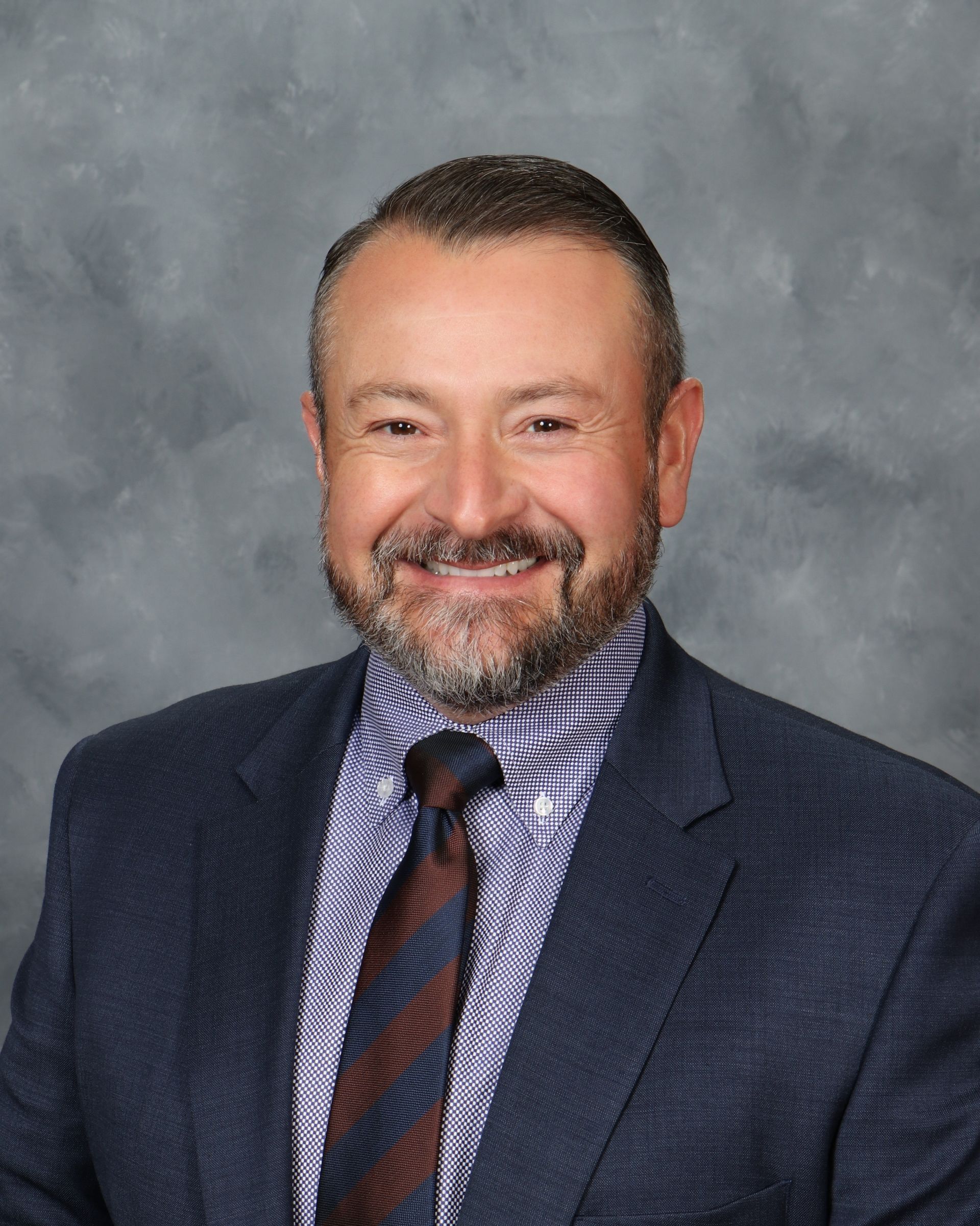 A man in a suit and tie is smiling for the camera.