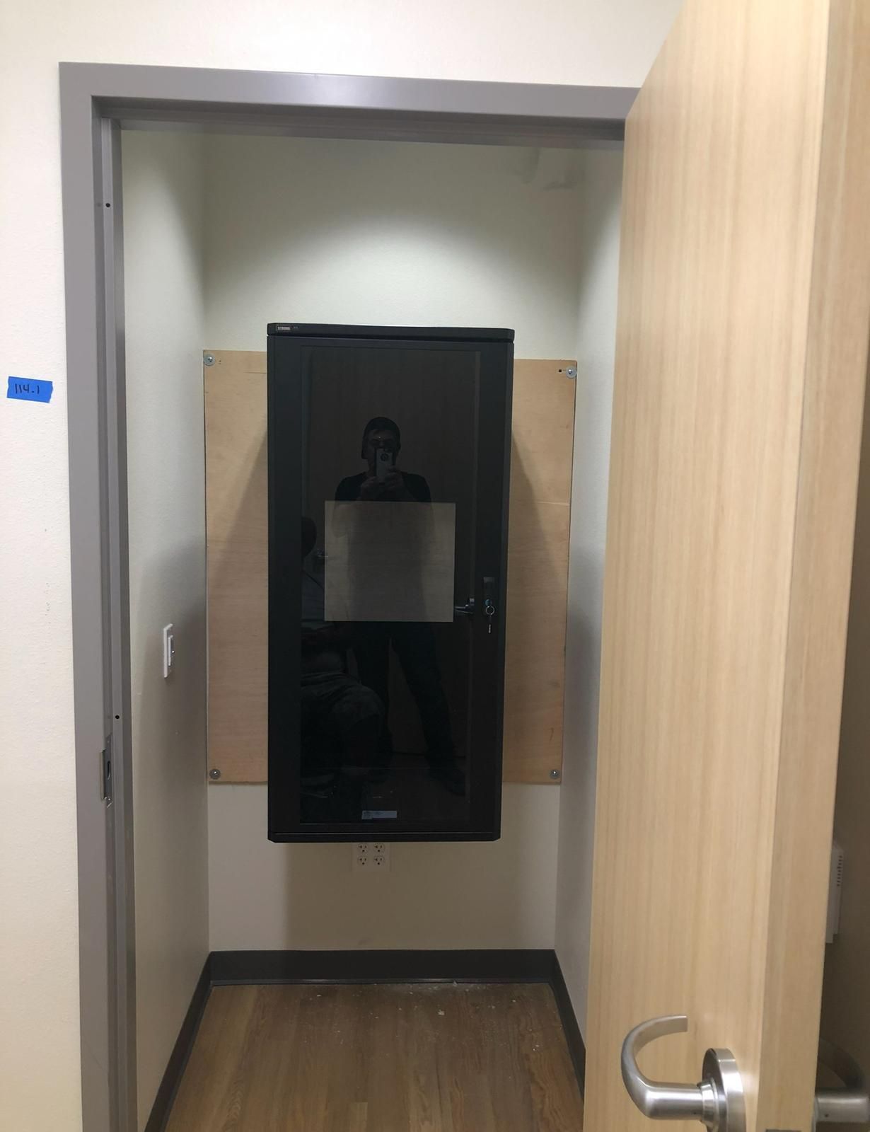Public restroom with a black baby changing station mounted on the wall, viewed through an open stall door.