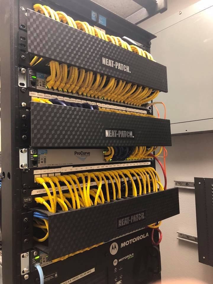 Server rack with stacked networking switches and many yellow Ethernet cables in a data center