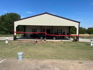 A car is parked in a garage under a metal building.