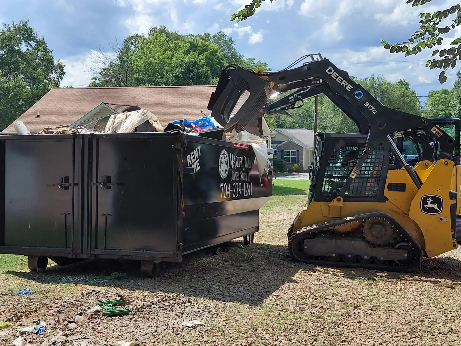 A bulldozer is loading trash into a dumpster.