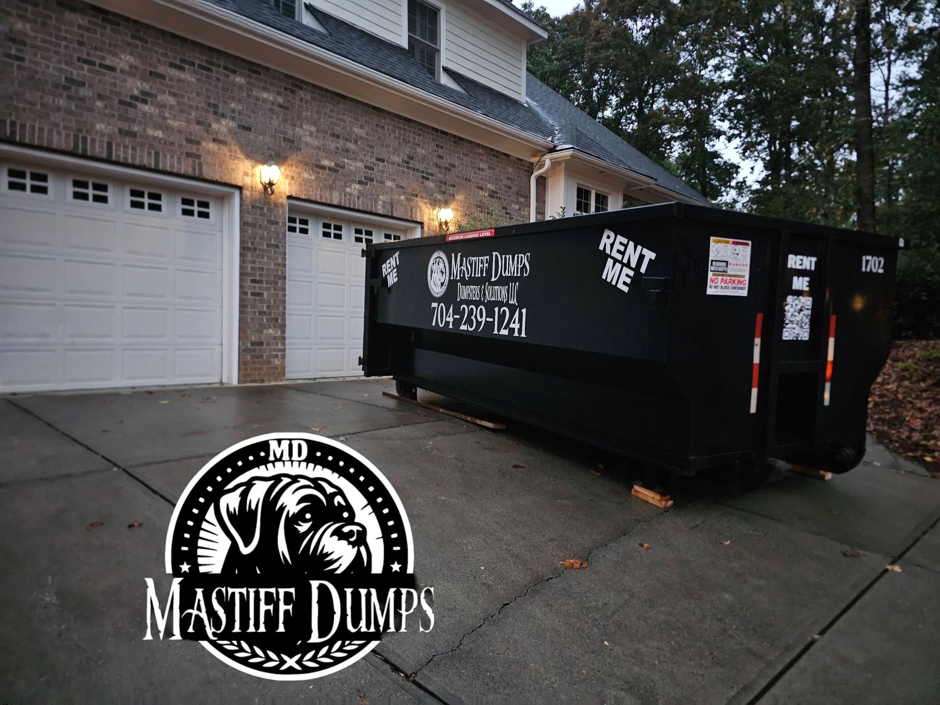 A dumpster is parked in front of a house.