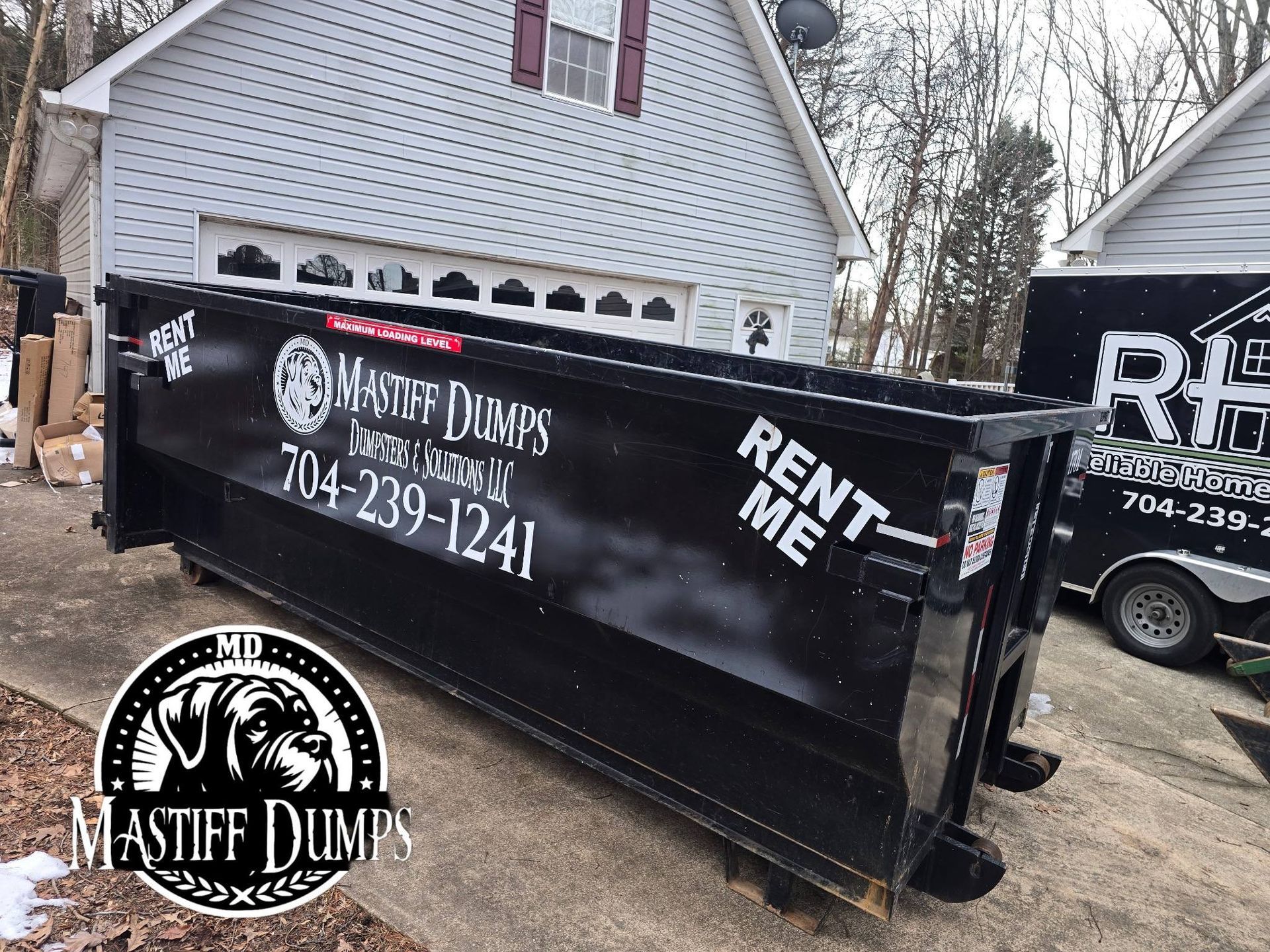 A dumpster is sitting in the grass in front of a building.