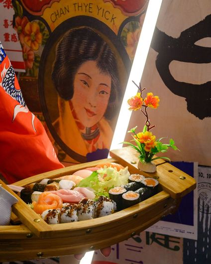 Piatto di sashimi con salmone, gamberi e abalone su ghiaccio, guarnito con foglie.