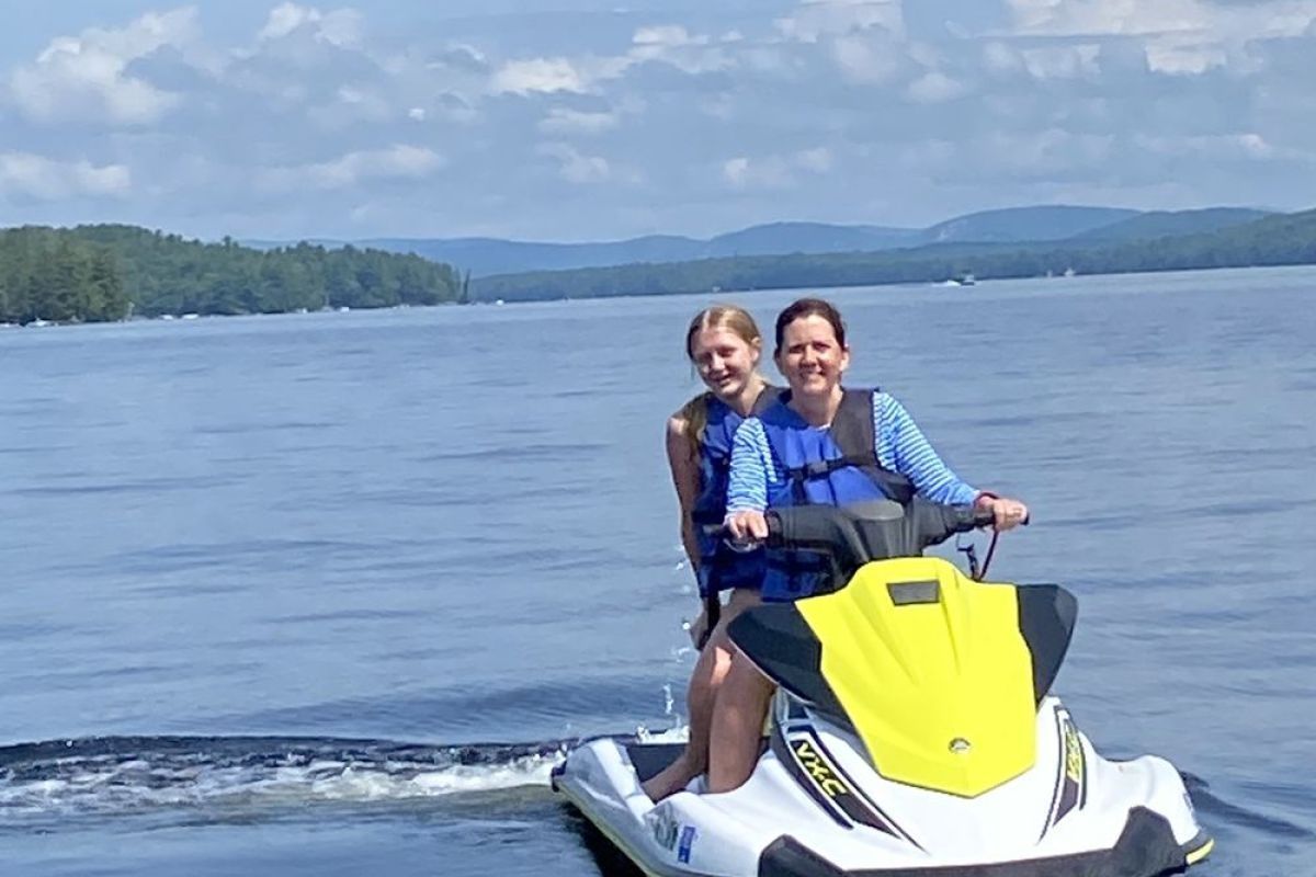 Two women are riding a jet ski on a lake.