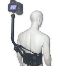 A mannequin wearing a black camera harness with a DSLR camera attached, positioned over its back.