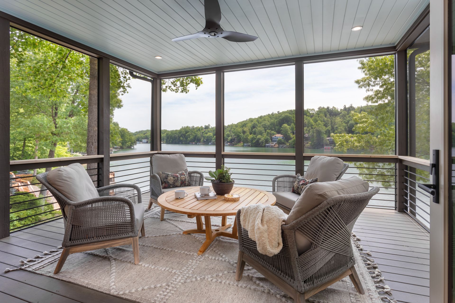 Screened porch with wicker seating and a lake view beyond the railing