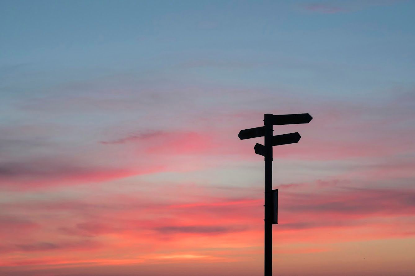 A traffic light is silhouetted against a sunset sky.