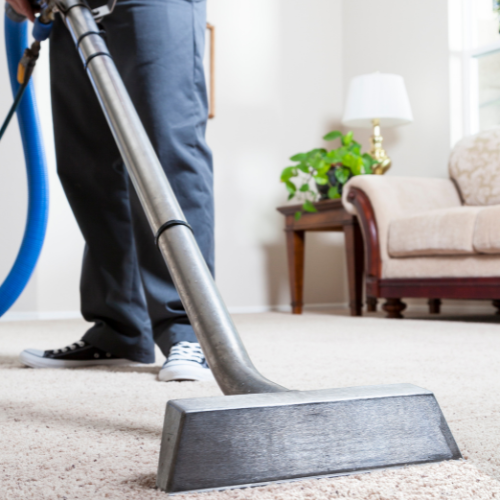 Person cleaning carpet with a professional machine in a living room.