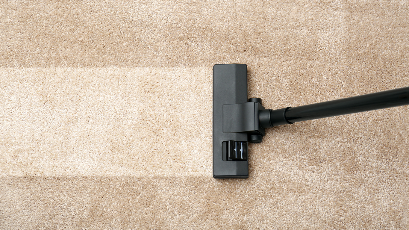 Vacuum cleaner cleaning a tan carpet, leaving a clean path.