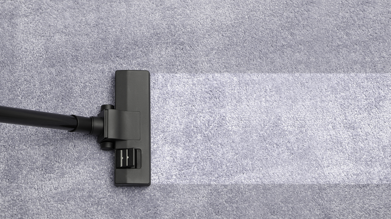 Vacuum cleaner cleaning a gray carpet, leaving a clean white path.
