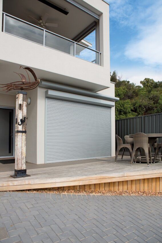 A White House With A Gray Garage Door And A Balcony — Mid Coast Flooring & Blinds In Taree, NSW