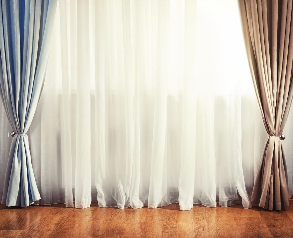 A Pair of Curtains Are Hanging on a Window in a Living Room — Mid Coast Flooring & Blinds In Wingham, NSW