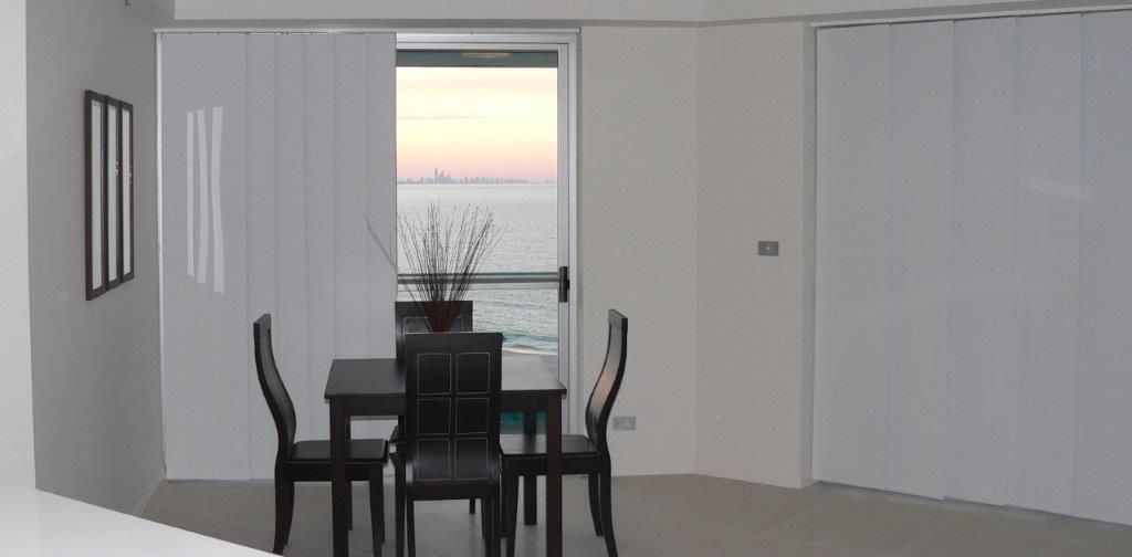 A Dining Room With A Table And Chairs And A View Of The Ocean — Mid Coast Flooring & Blinds In Taree, NSW