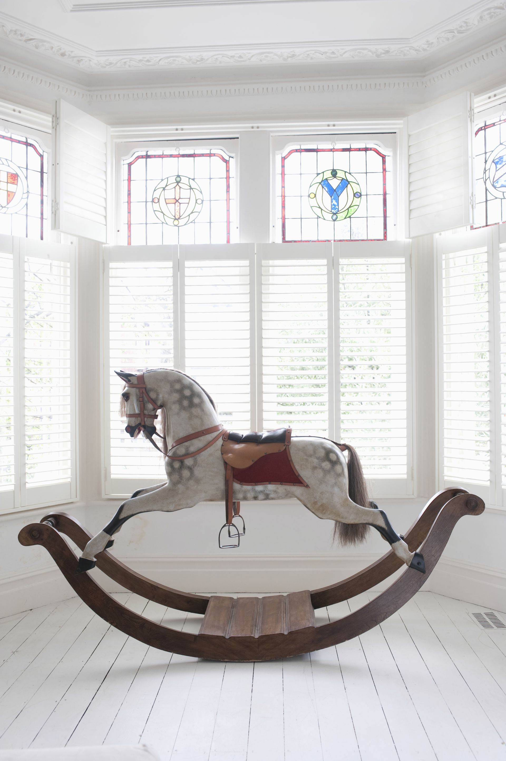A Rocking Horse Is Sitting In Front Of A Window In A Room — Mid Coast Flooring & Blinds In Taree, NSW