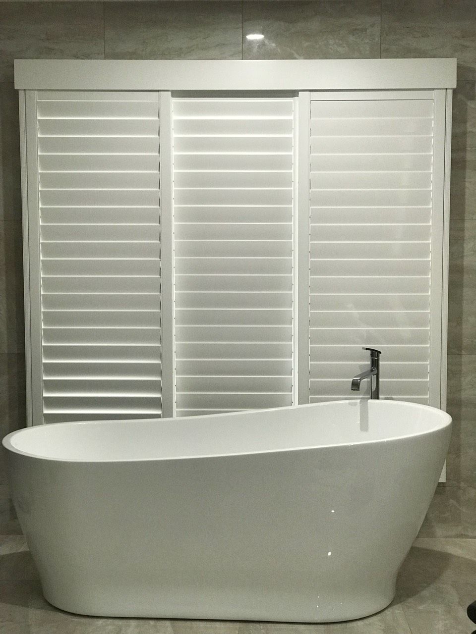 A Bathroom With A Bathtub And Shutters On The Window — Mid Coast Flooring & Blinds In Taree, NSW